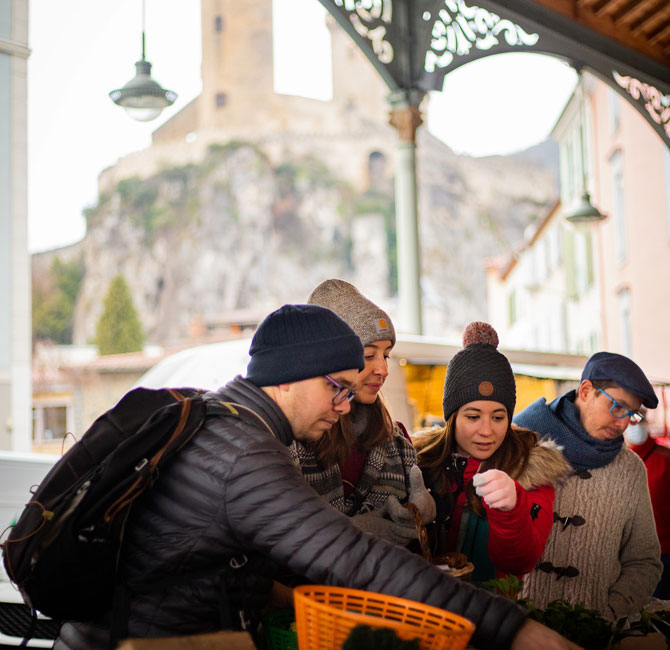 Groupe d'amis au stand de fruits et légumes du marché de Noel de Foix